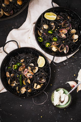Dinner for two: black pasta with clams served in fry pans with double handles. Top view