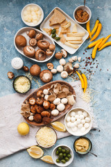 Ingredients of fresh variety mushrooms, cheeses yellow spicy peppers and pickles  over a blue table