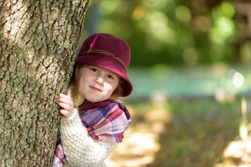 Unimaginably beautiful blond girl in a hat, playing hiding behin
