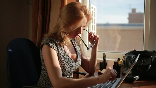 Busty sexy business woman working for a laptop. sucks glasses