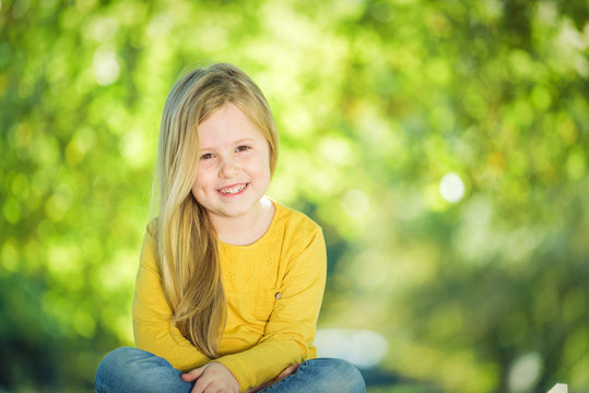 Sympathetic and beautiful little girl on a bench in a park in th