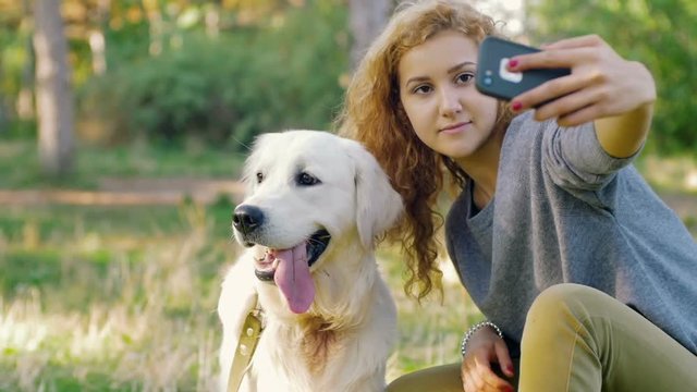 Young female doing selfie with labrador retriever dog in park