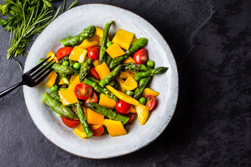 Vegetarian salad with asparagus, cherry tomatoes, bell pepper, slate background