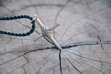 Silver cross on old wood with cracks.