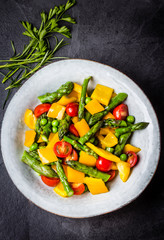 Vegetarian salad with asparagus, cherry tomatoes, bell pepper, slate background