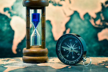 Compass and hourglass on grunge world map