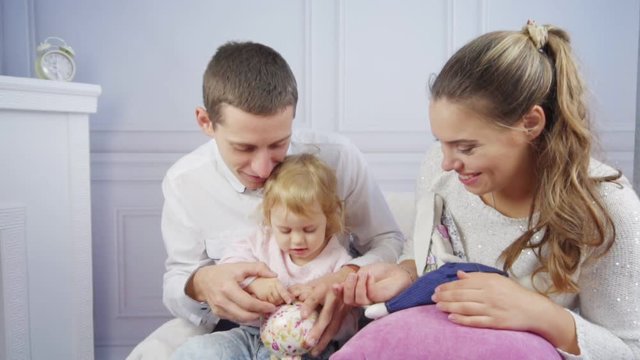 Young family with cute babygirl plays with money box