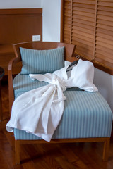 Fototapeta na wymiar clean bathrobe on sofa bed in upscale hotel. white bathrobe on the bed prepare to use in pool villa hotel. Image with shadow