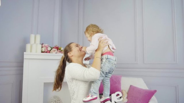 Mother plays with her baby girl embracing and kissing