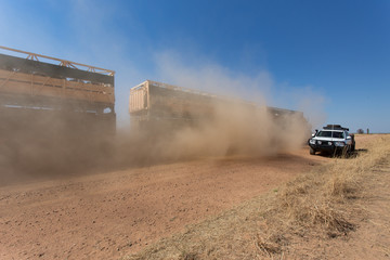 Double deck cattle road train passing a 4WD  on dusty outback ro