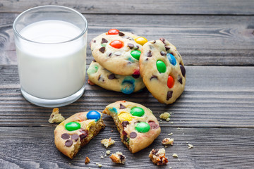 Shortbread cookies with multi-colored candy and chocolate chips, served with glass of milk, horizontal, copy space