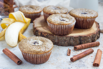 Freshly baked homemade banana cinnamon muffins with slice of banana on top, on wooden board