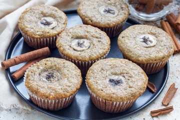 Freshly baked homemade banana cinnamon muffins with slice of banana on top, on the tray