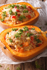 half baked pumpkin with couscous, meat, vegetables and cheese close-up. vertical