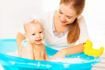 Happy family mother bathes the baby in  bath
