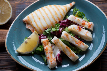 Grilled calamari salad served in a turquoise plate, close-up