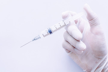 Hand in a rubber glove holding syringe