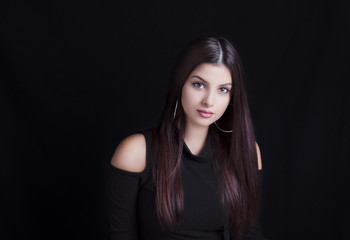 Fototapeta premium Young attractive woman with long black hair on black background.