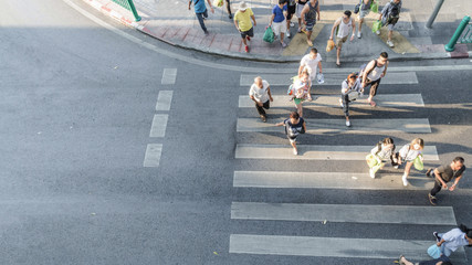 Blur people are moving across the pedestrian crosswalk in the city road (on top view)