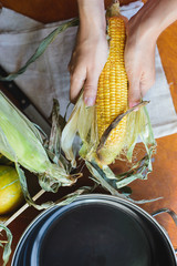 top view of woman prepares corn for cooking in bowl