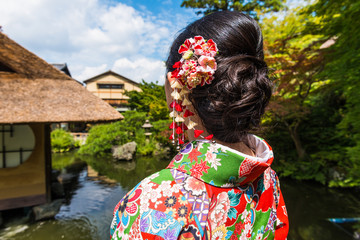 Women in kimonos stand in Kyoto ancient architecture to admire Maple Leaf