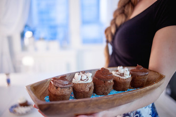 girl holding plate of fresh hot muffins, blurred background