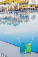 Fototapeta na wymiar Fresh alcoholic cocktails near the swimming pool at resort. Blue and green longdrinks with ice.