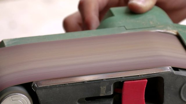 Belt sander / Process of grinding the wooden piece on the belt sander, close-up