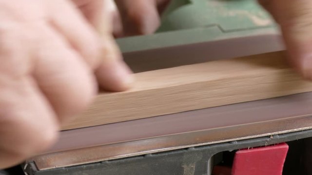 Belt sander / Process of grinding the wooden piece on the belt sander, close-up