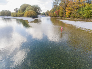 Luftbild Drohnenflug Mann in Badehose steht in  Fluss und schaut