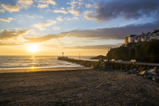 Sunrise at Looe beach with clouds in the sky and golden colours, Cornwall, UK