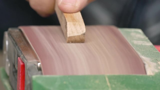 Belt sander / Process of grinding the wooden piece on the belt sander, close-up