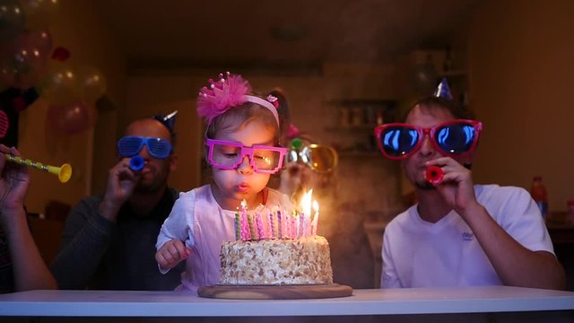 Little girl blows out candles on the birthday cake slow motion