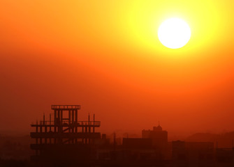 Fototapeta premium Setting sun behind construction building