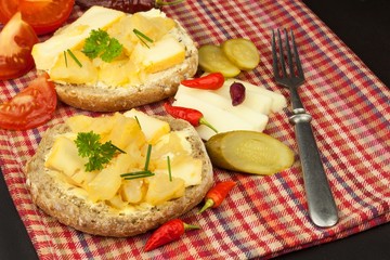 Two kinds of cheese on bread. Healthy breakfast on the kitchen table. Bread with cheese cherry tomato and chilli. 
