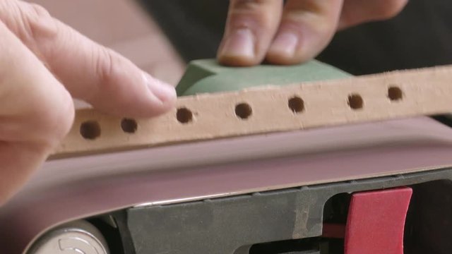 Belt sander / Process of grinding the wooden piece on the belt sander, close-up