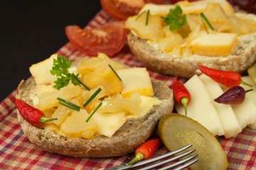 Two kinds of cheese on bread. Healthy breakfast on the kitchen table. Bread with cheese cherry tomato and chilli. 

