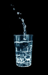 Glass of Water with Ice and Splashes isolated on black