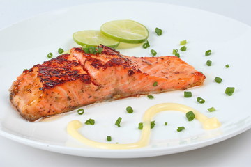 Close up of grilled salmon topped minced shallot ,mayonnaise and sliced lemon on white dish. Selective focus.