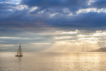 Small sailboat sailing on the lake Leman (Switzerland) at sunset
