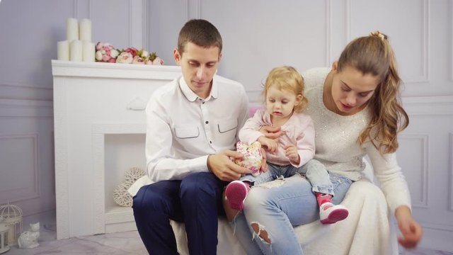 Young family plays with their baby girl at home at fire place