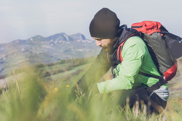 Hiker is looking at flowers on the ground