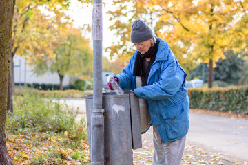 Indigent senior woman scrounging through a bin