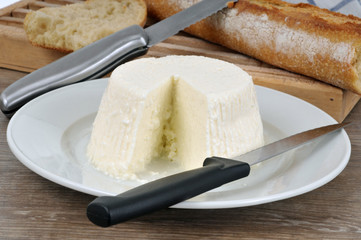 Fromage brousse entamé posé sur une assiette avec un couteau et du pain