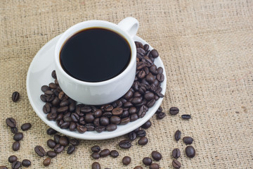 White cup with coffee drink on jute bag background