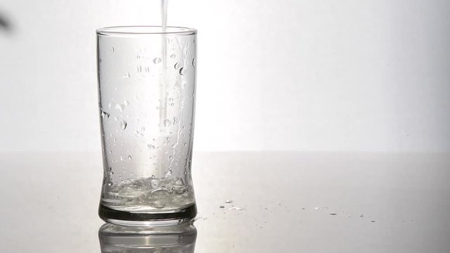 Pouring water in glass on white background and leaf shadow