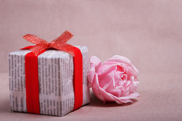 Gift box in a newspaper packaging with a rose on a background scrapbook paper