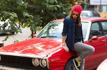 Pretty stylish woman standing by the retro car