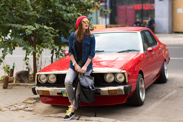 Pretty stylish woman standing by the retro car