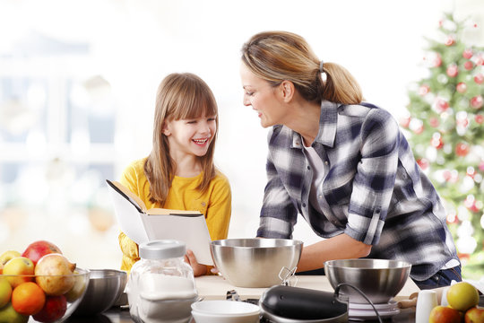 Christmas Time. Portrait Of Cute Daughter And Her Mom Baking Christmas Cookies Together In The Kitchen.